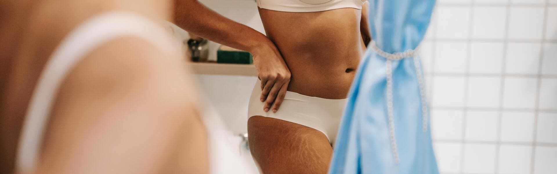 Kvinna i underkläder speglar sig i badrumsspegel. Kvinna i underkläder speglar sig i badrumsspegel.