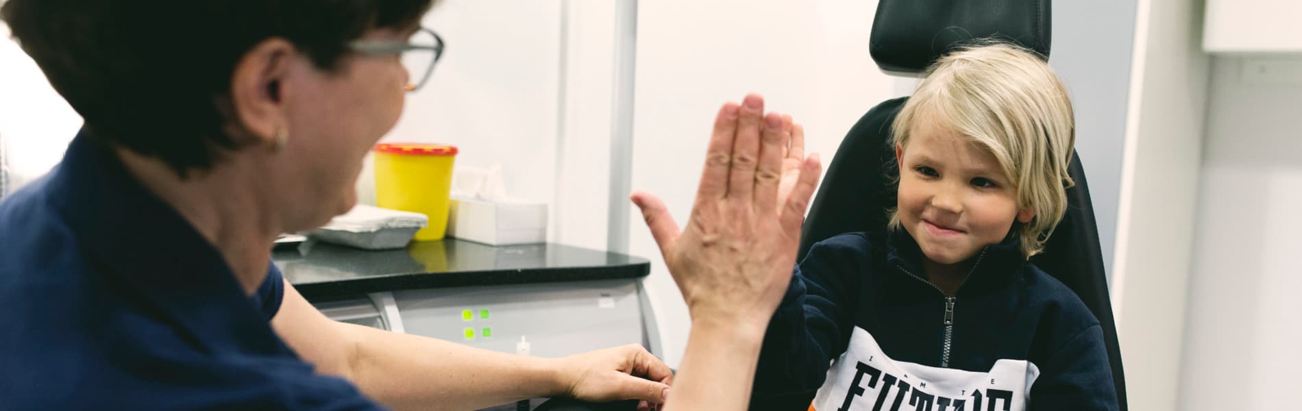 Läkare gör high five med barn efter undersökning