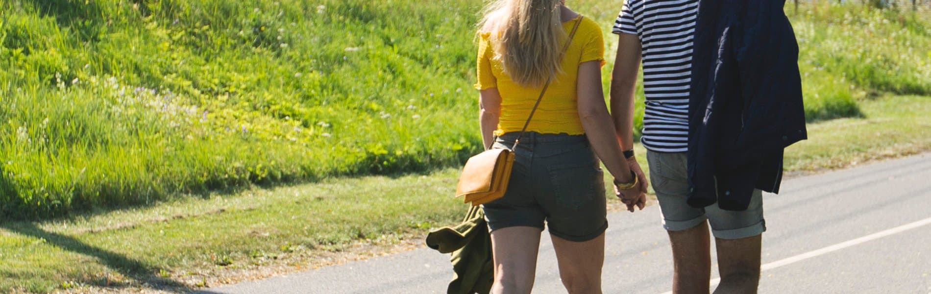 Promenerande par håller varandra i handen