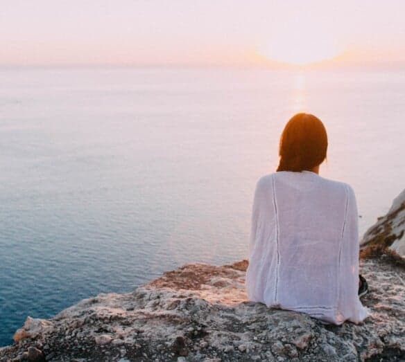 Kvinna som sitter vid havet