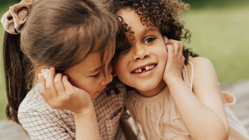 Två flickor Närbild av två flickor utomhus i somrig miljö