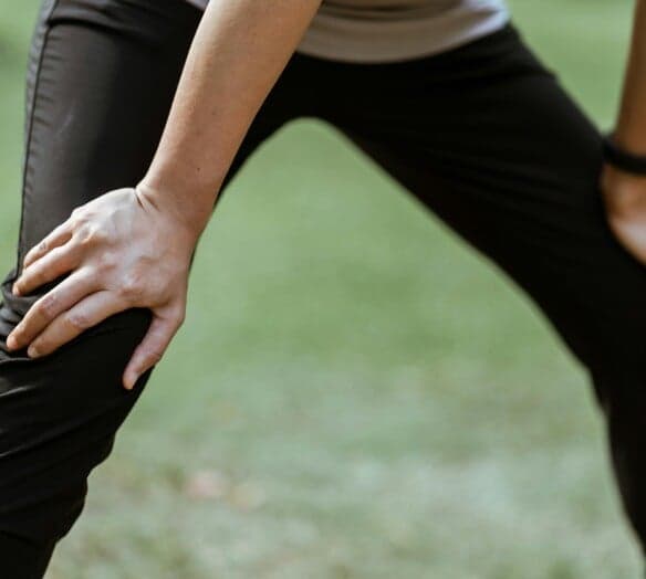 Stående kvinna håller händerna på sina knän Stående kvinna håller händerna på sina knän