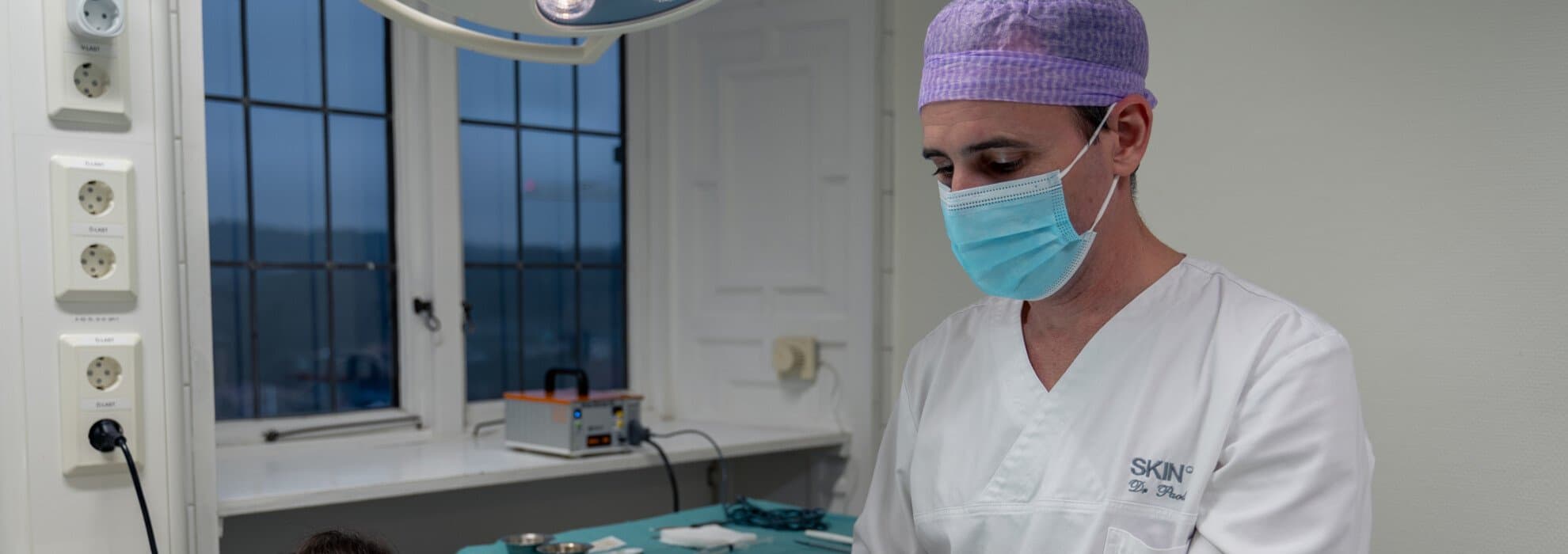 Kirurg med munskydd opererar Kirurg med munskydd opererar