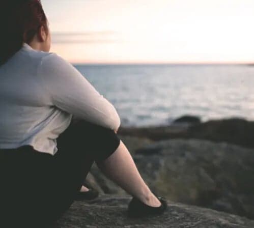 Kvinna sitter på ett berg vid havet Kvinna sitter på ett berg vid havet