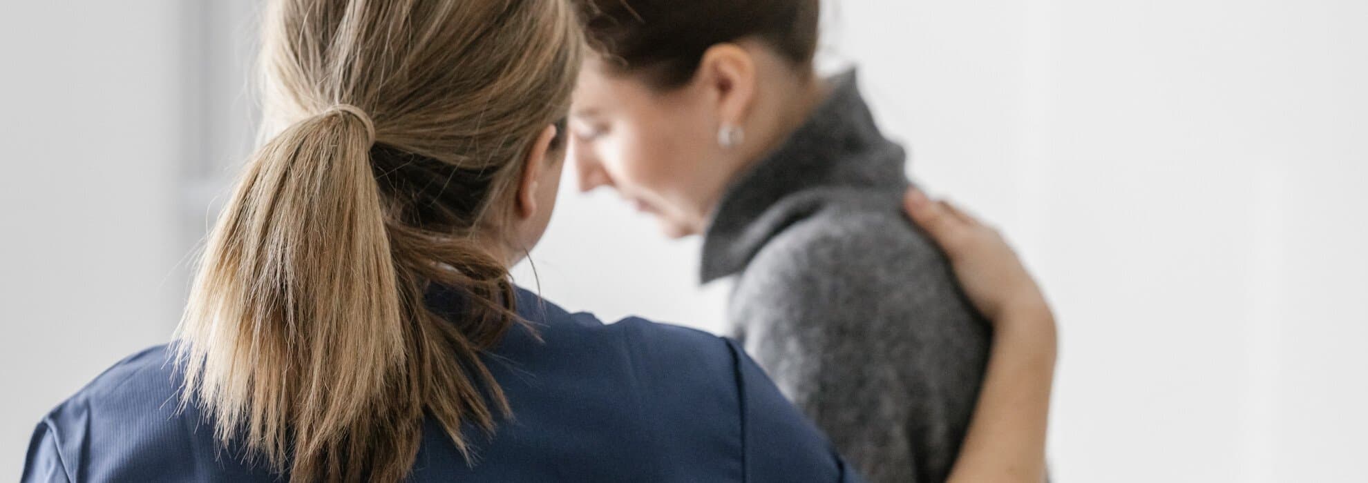 Kvinna håller hand på annan kvinnas rygg