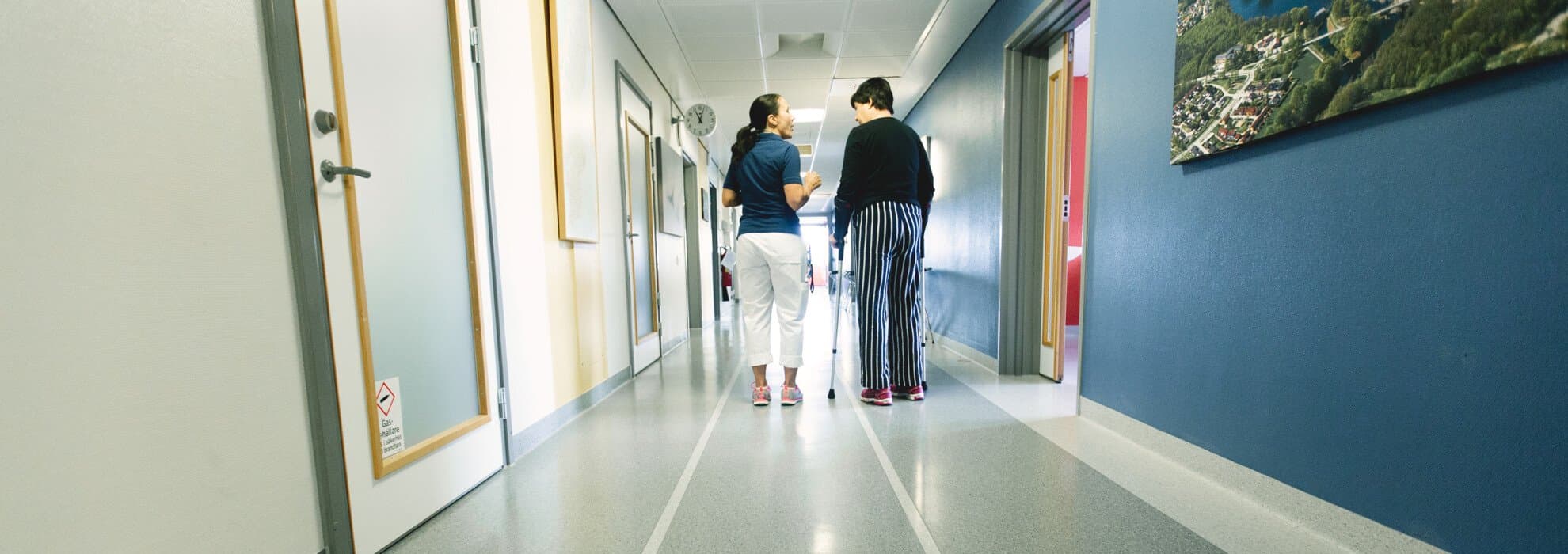 Medarbetare går i korridor tillsammans med patient