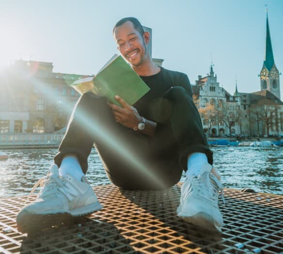 Man sitter vid vattnet och läser en bok Man sitter vid vattnet och läser en bok