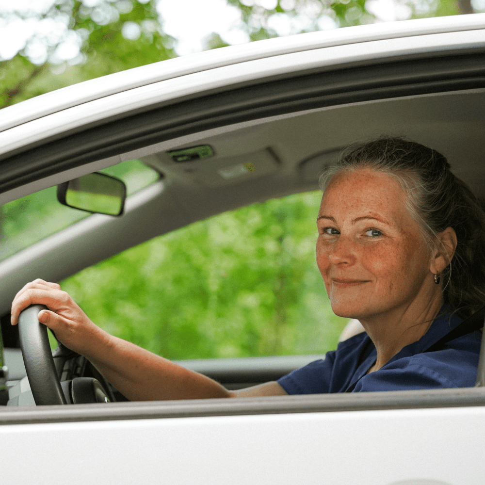 Kvinna i bil som tittar ut och ler
