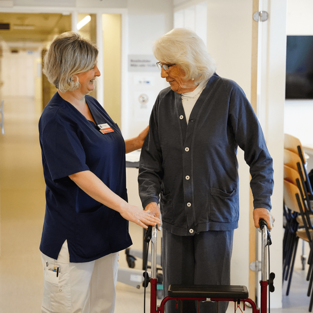 Kvinna med rullator tillsammans med vårdpersonal